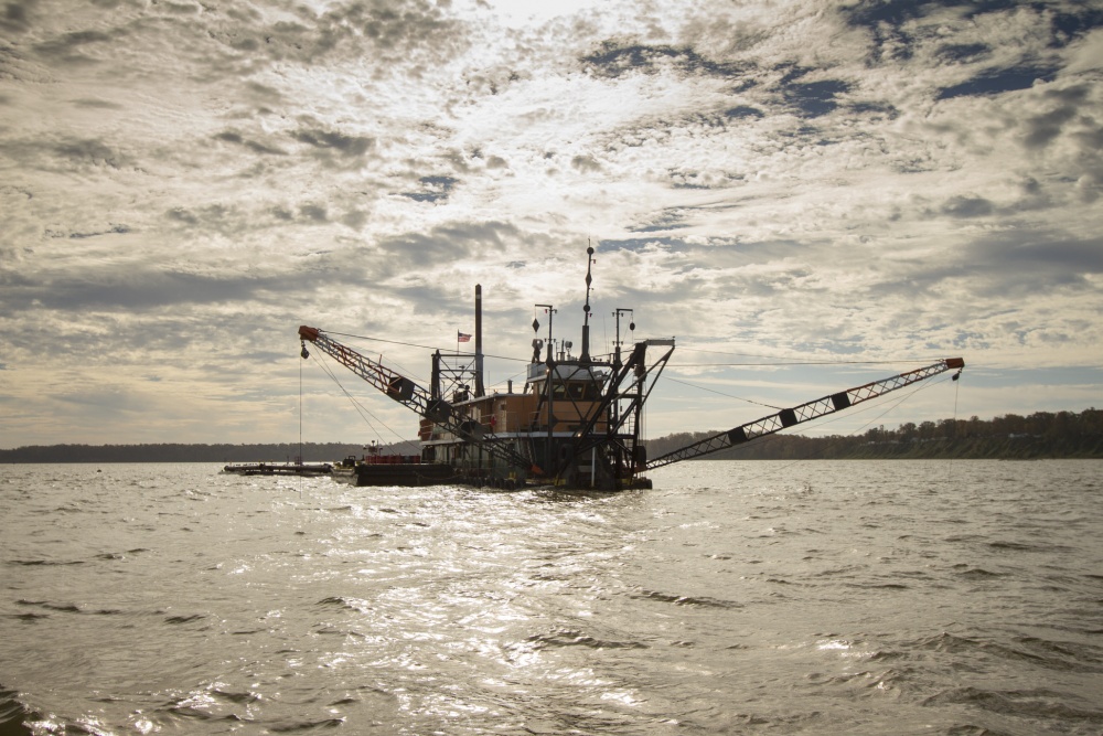 NDC-Dredge working with clouds and sun behind